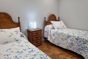 Un dormitorio con dos camas de madera, una mesita de noche y una lámpara de noche.