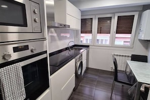 A compact kitchen with a built-in oven, microwave, and washing machine.