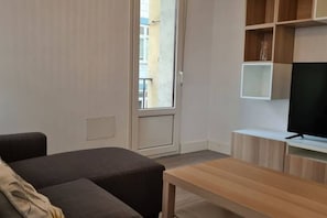 A modern living room with a sofa, a coffee table, and a TV on a wooden stand.