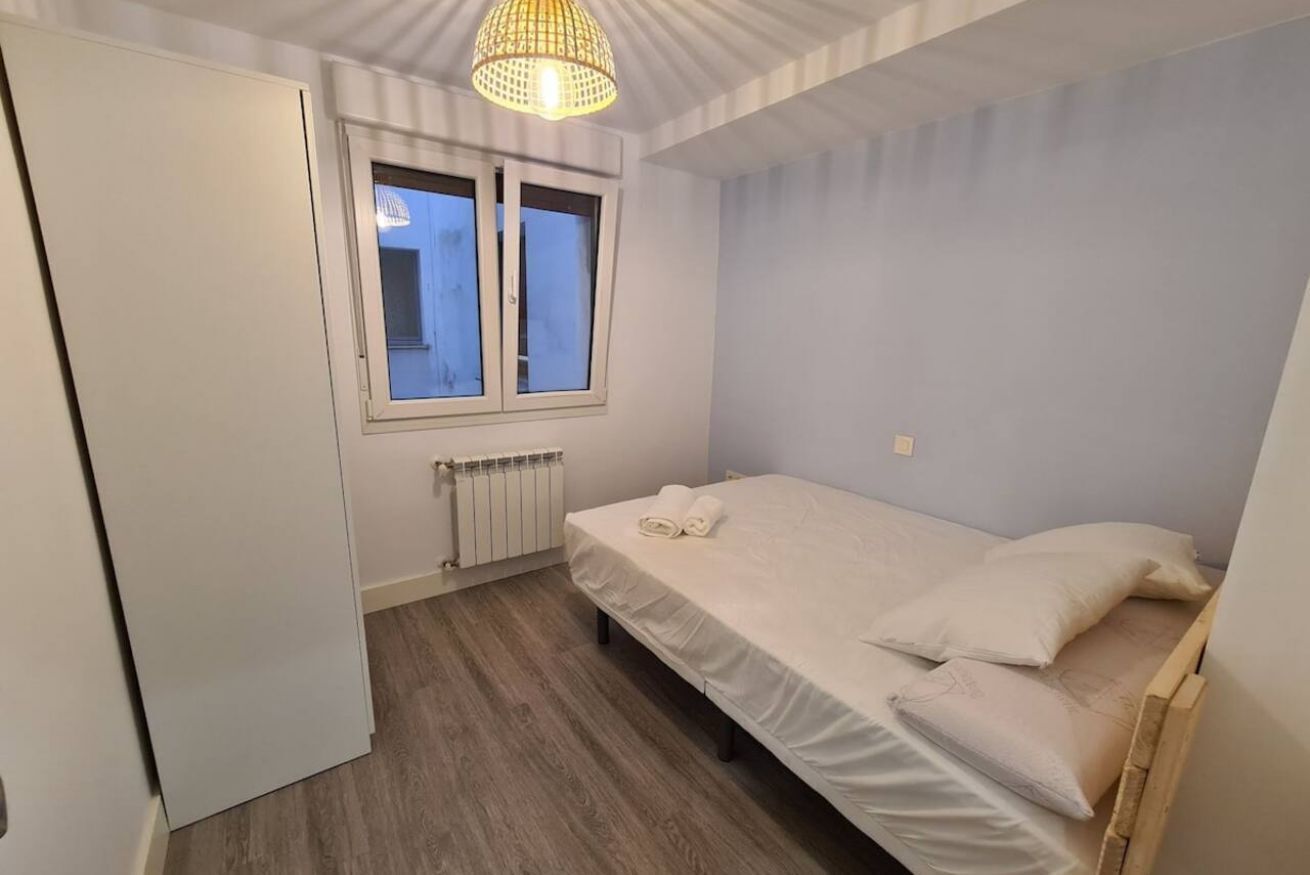 A bedroom with a bed, a window, a radiator, and a wardrobe.