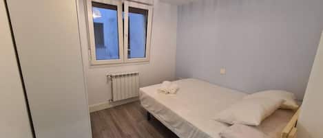 Et soveværelse med en seng, et vindue, en radiator og et klædeskab.