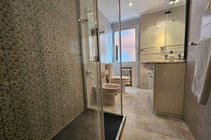 Une salle de bain moderne avec une douche à parois de verre, des toilettes et un lavabo avec un miroir.