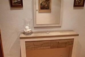 Un baño con encimera de mármol, un cuadro enmarcado sobre el espejo y un mueble debajo.