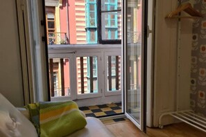 A room with a sliding glass door leading to a balcony, a checkered floor, and a hanging coat rack. - 122A Iconic Home in Playa San Lorenzo (Gijón)