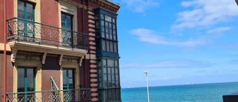A multi-story building with a balcony overlooking a beach.