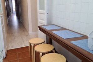 A hallway with a wooden bench and stools, a tiled wall, and a door leading to another room. - 122A Iconic Home in Playa San Lorenzo (Gijón)