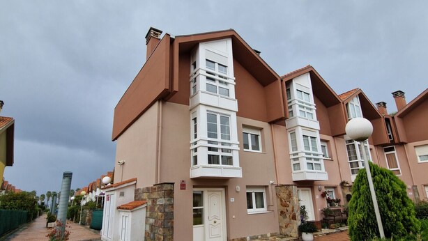 A residential building with a central tower, multiple windows, and a paved walkway.