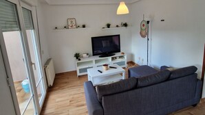 A living room with a sofa, a television, a coffee table, and a pendant light.