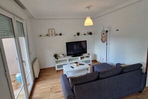 A living room with a sofa, a television, a coffee table, and a pendant light. - 158A Rinconin Triplex with Pool (Gijón)