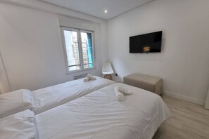 Een hotelkamer met twee bedden, een televisie, een raam met uitzicht en een kleine stoel.