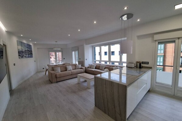 A spacious living area with a sofa set, a coffee table, and a kitchen island.