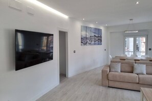 A modern living room with a flat-screen TV, a beige sofa, and a large abstract painting on the wall.