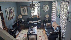A living room with a sofa, coffee table, and a clock on the wall. - The Red Mill House (Goldsboro)