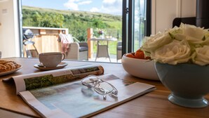 A table with a bowl of white flowers, a cup, a pair of glasses, and a newspaper. - Little Heaning (Grange-over-Sands)