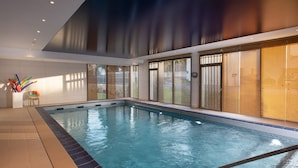 An indoor swimming pool with clear water, surrounded by large windows with blinds, and a tiled floor. - Maison Douaud Vannes (Vannes)