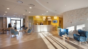 A modern hotel lobby with a reception desk, seating area, and a patterned wall. - Maison Douaud Vannes (Vannes)