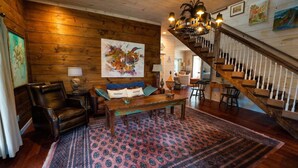 A wooden-floored living room with a sofa, a coffee table, and a staircase with white balusters. - High Point Retreat in the Heart of Mentone! (Mentone)