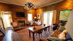 A cozy log cabin interior with a fireplace, wooden floors, a dining table, and comfortable seating. - High Point Retreat in the Heart of Mentone! (Mentone)