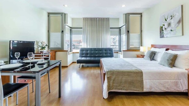 Una habitación de hotel con una cama, un escritorio con televisor y una silla.