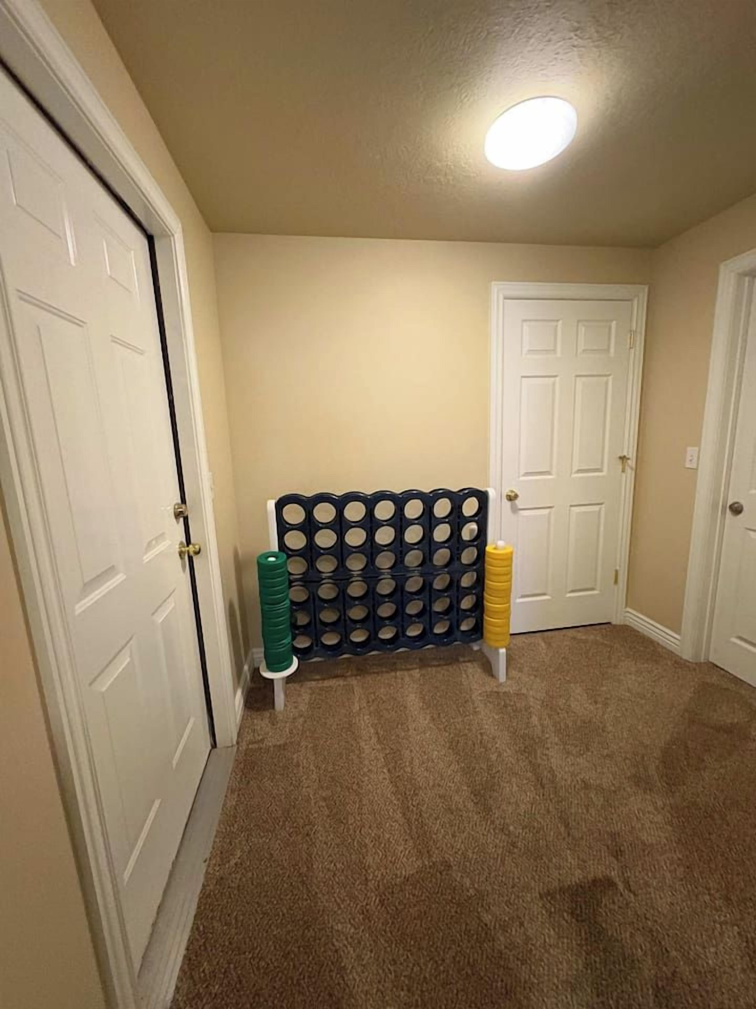 A hallway with carpeted flooring, a wall-mounted rack with circular holes, and white doors.