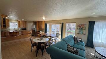 A spacious living area with a sofa, dining table, and kitchen in the background.