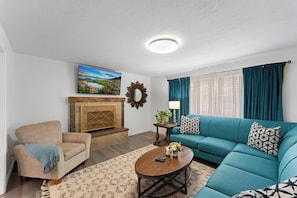 Main floor living room with a teal sectional and brick fireplace - Huge Yard, Pet-Friendly Gathering Home.Waffles too (Orem)