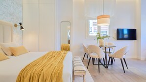 Ein modernes Hotelzimmer mit einem großen Bett, einem Nachttisch und einer Sitzecke mit Stühlen und einem kleinen Tisch.