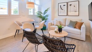 Ein modernes Wohnzimmer mit einem runden Tisch, zwei Stühlen, einer Couch und einem Fernseher.
