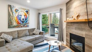 A modern living room with a sectional sofa, a fireplace, and a large window with curtains.
