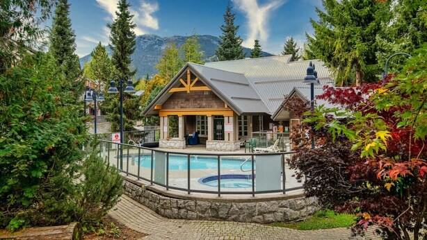 A lodge with a pool, surrounded by trees and mountains.