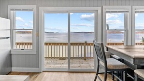 A room with a view of a body of water through large sliding glass doors. - Beach House · Beautiful Beachfront House, Close to Burlington! (Colchester)