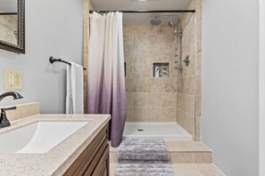 A bathroom with a shower, a sink, and a mirror. - Beach House · Beautiful Beachfront House, Close to Burlington! (Colchester)