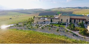 A building with a courtyard, surrounded by fields and hills.