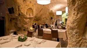 A restaurant with tables set for dining, stone walls, and a chandelier.