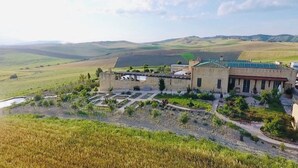 Un bâtiment doté d’une cour intérieure, entouré de champs et de collines.