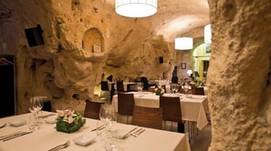Een restaurant met gedekte tafels, stenen muren en een kroonluchter.