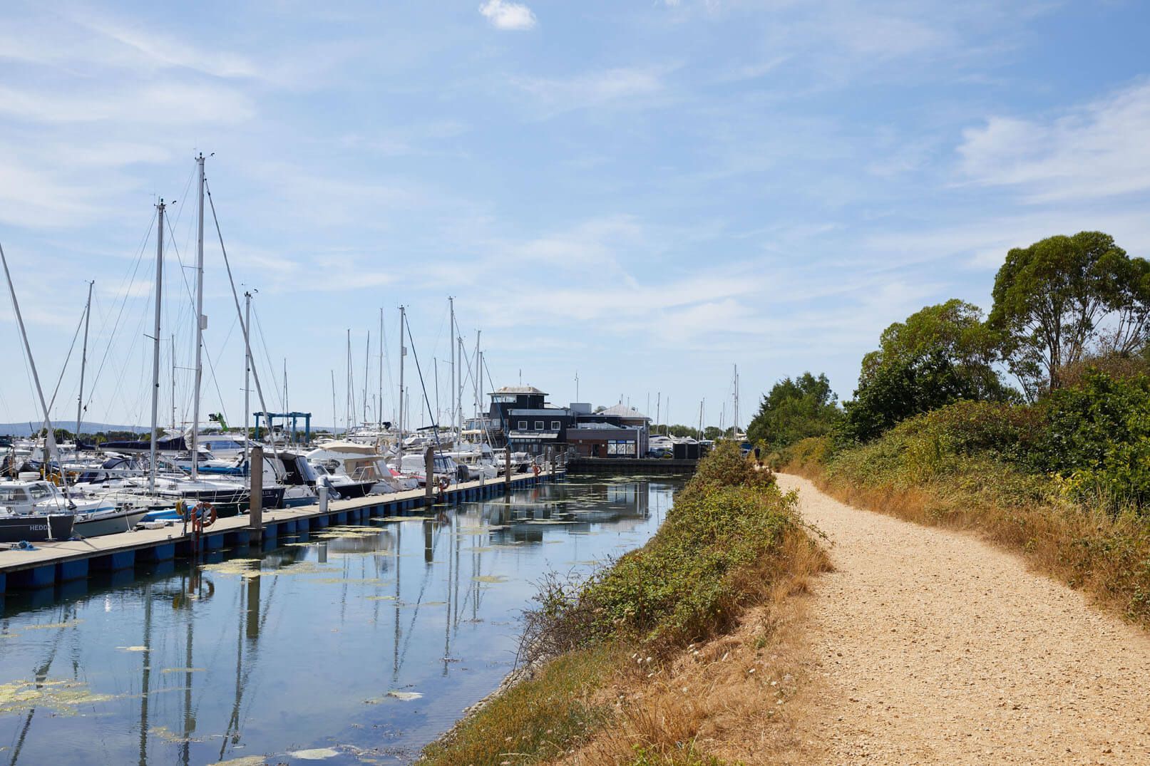 Un puerto deportivo con barcos amarrados a lo largo de un sendero de tierra.
