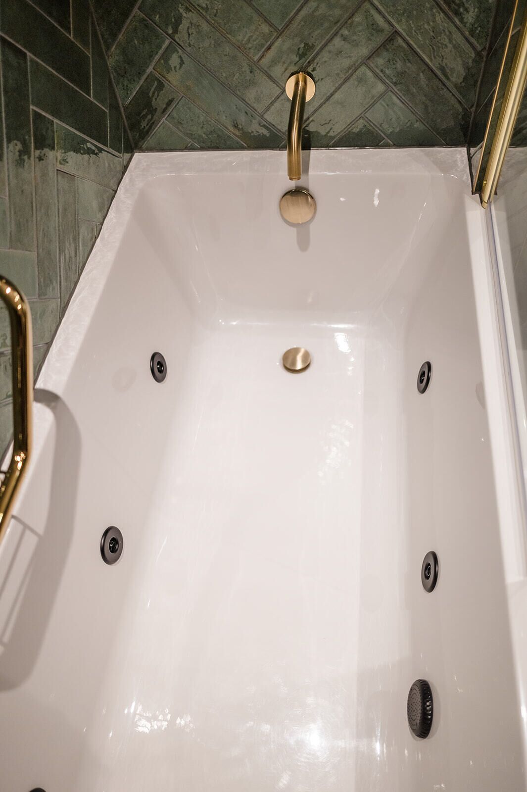 Una bañera blanca con detalles dorados y un desagüe en el centro.