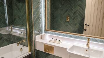 A bathroom with two sinks, a mirror, and a toilet. The walls have a herringbone tile pattern.