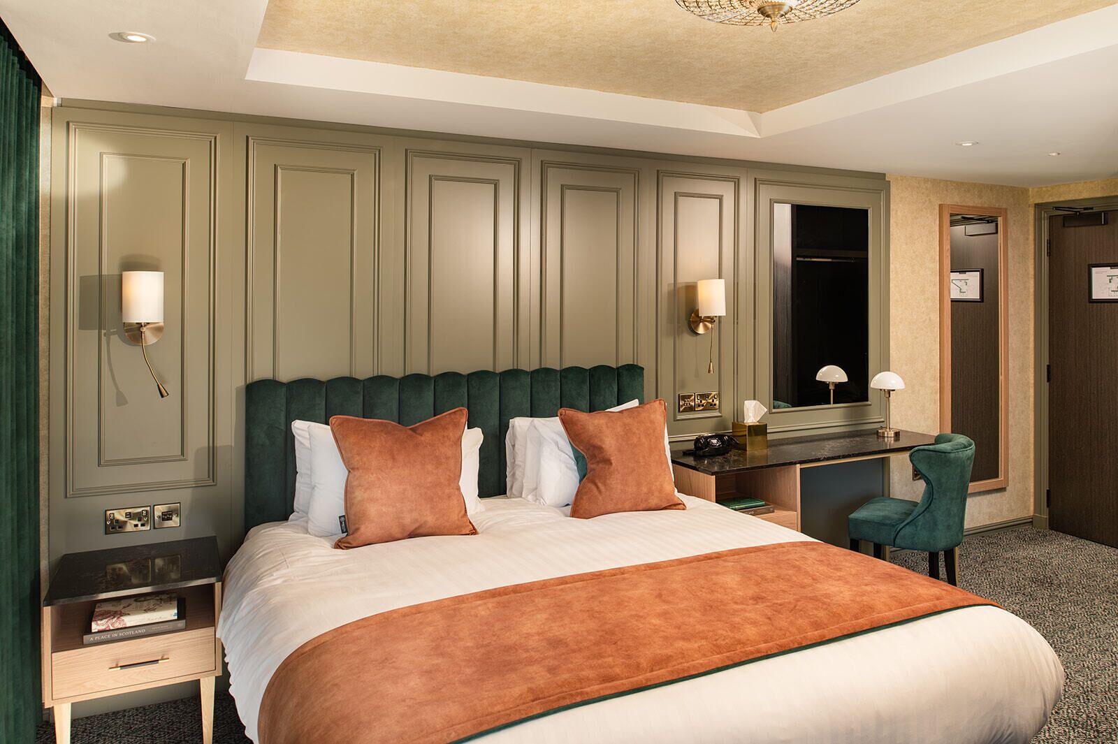 A hotel room with a large bed, a desk, and a chair.