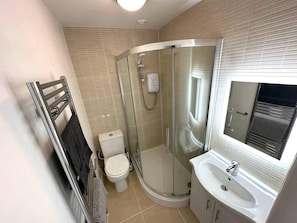 A modern bathroom with a glass-enclosed shower, a toilet, and a sink with a mirror. - Cosy and Quirky House in the Heart of Bakewell (Bakewell)