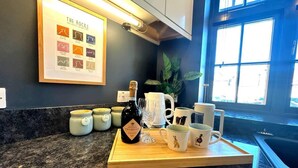 Een keukenblad met een fles biologische prosecco, koffiemokken en een lijst met een kaart van de rotsen.
