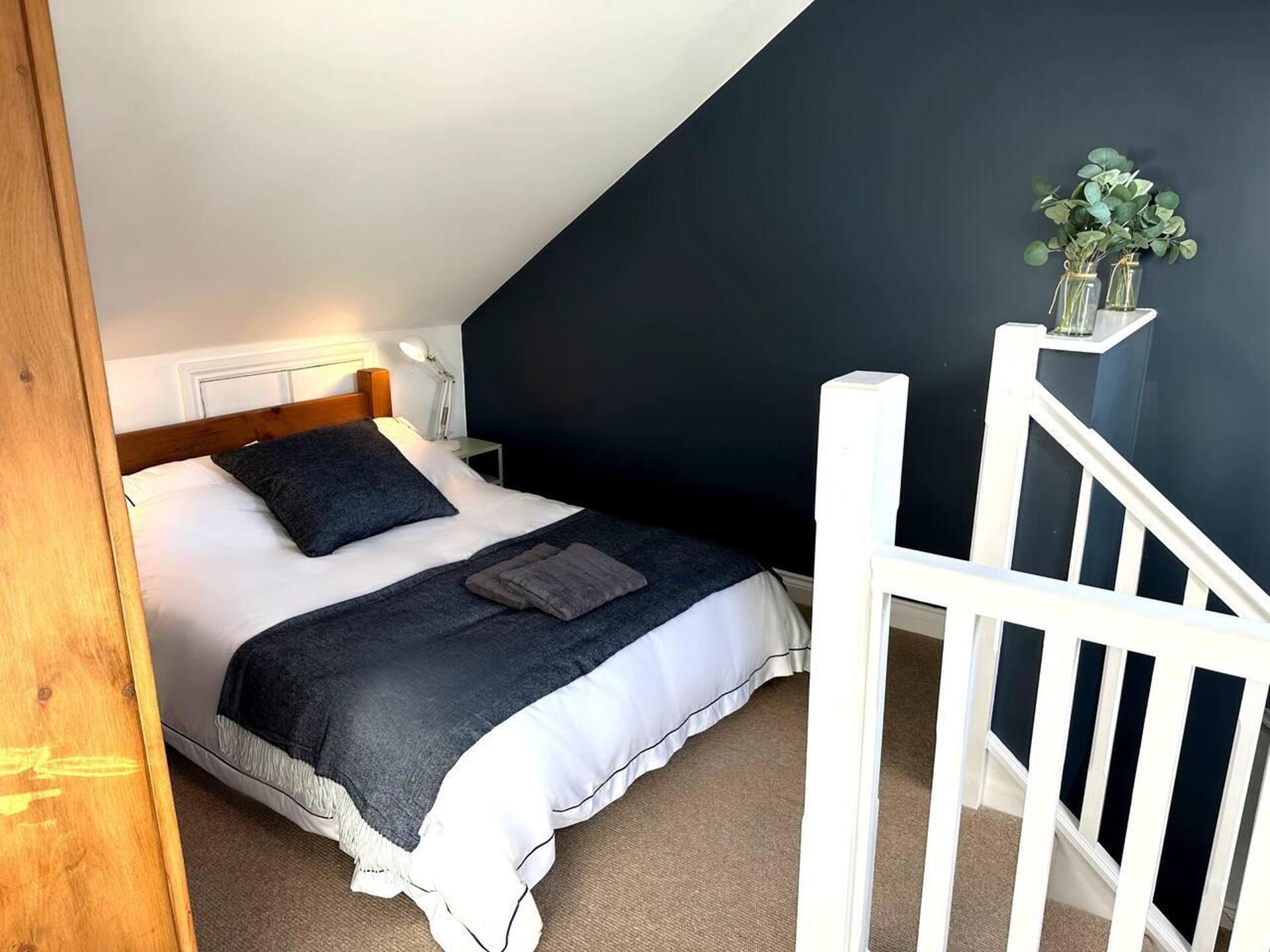 Une chambre à coucher avec un lit, une table de chevet, une lampe et un escalier.