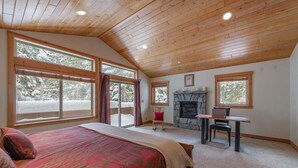 Ein Schlafzimmer mit einem großen Bett, einem Kamin aus Stein und einem Schreibtisch mit Computer.
