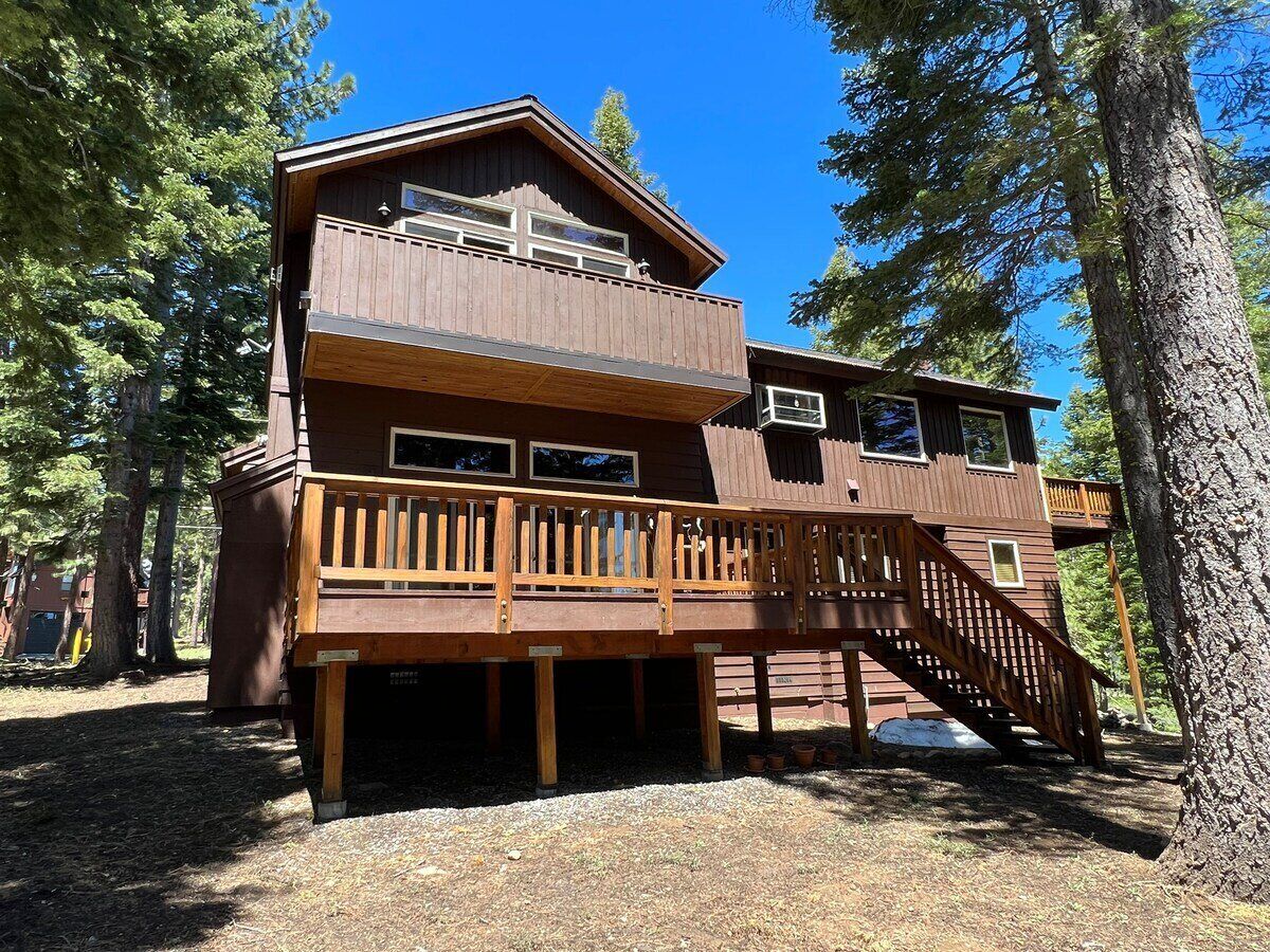 A multi-story wooden cabin with a balcony and a staircase.