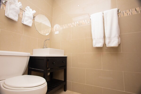 Un baño con inodoro, lavabo y dos toallas colgadas en la pared.