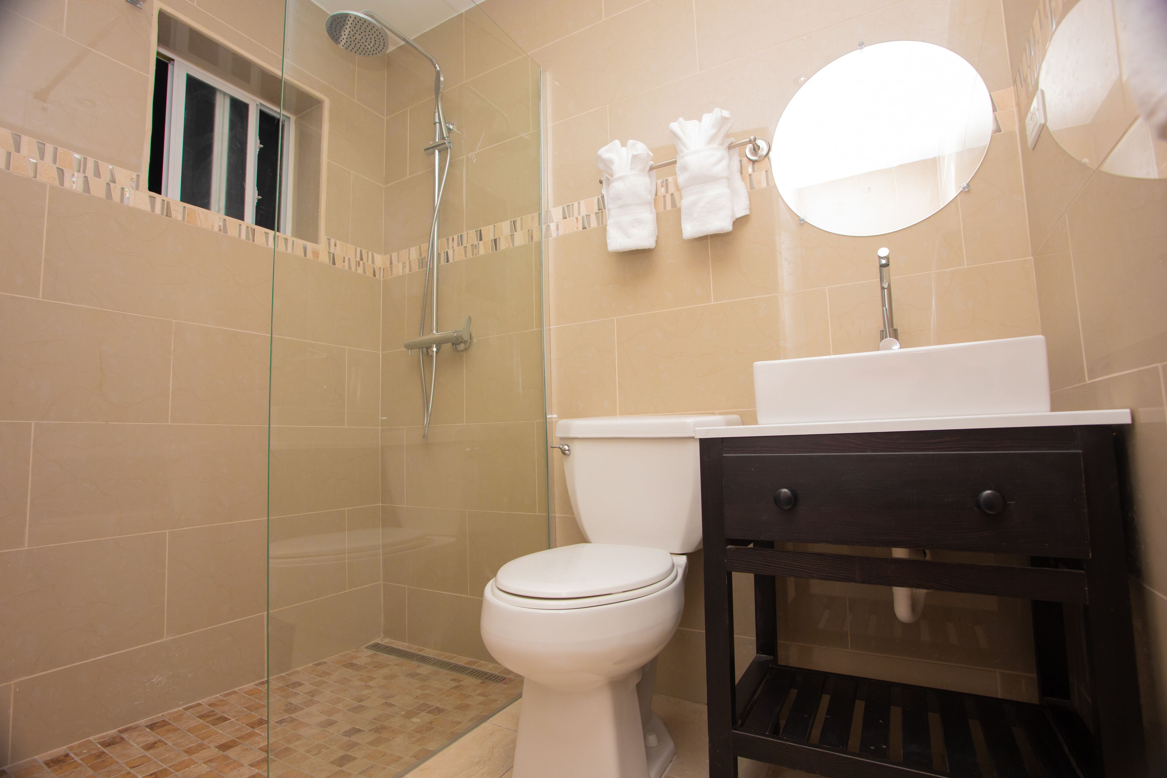Une salle de bain comprenant des toilettes, un lavabo, un miroir et un espace douche.