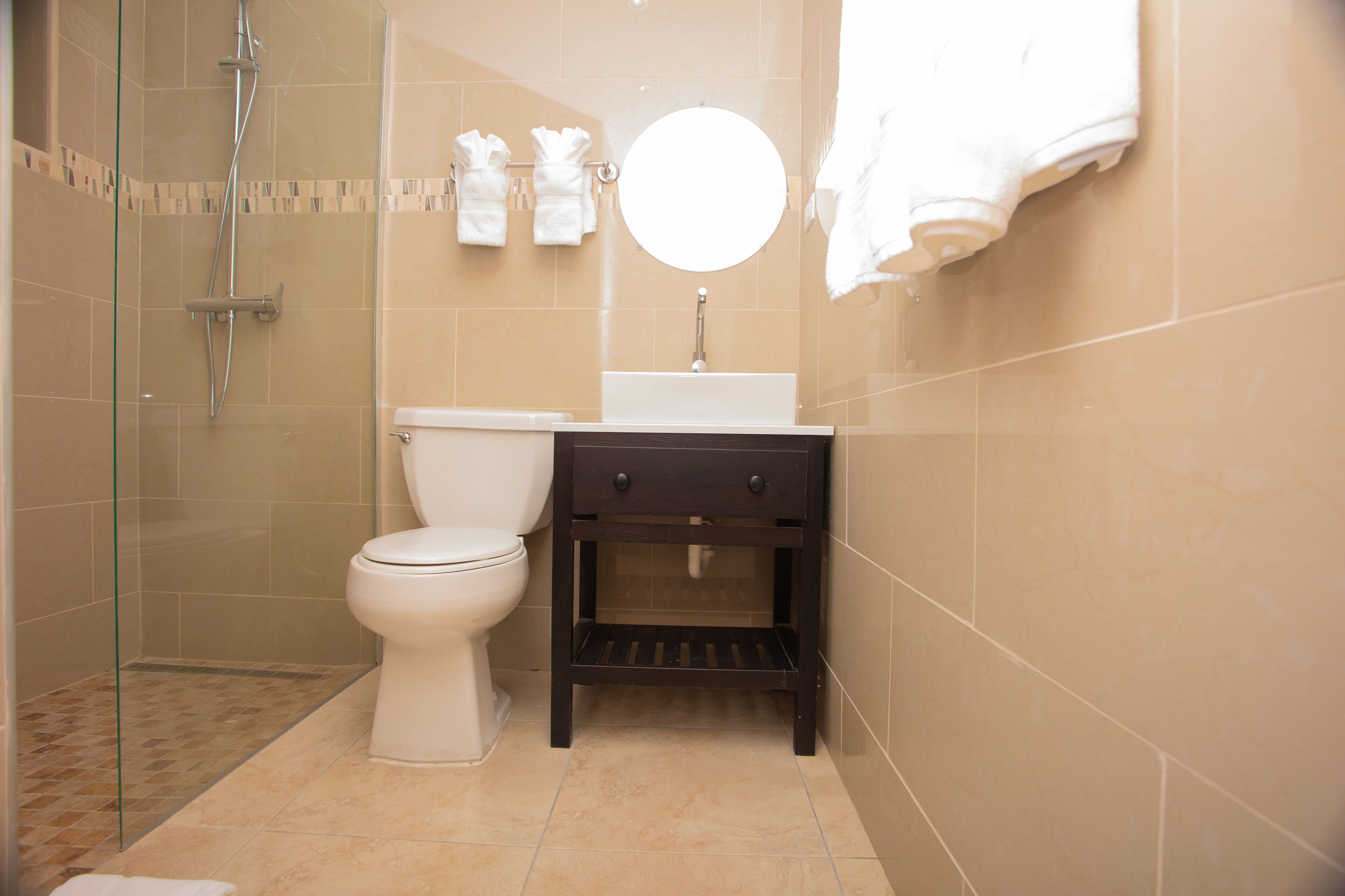 A bathroom with a toilet, a sink, a mirror, and a shower.