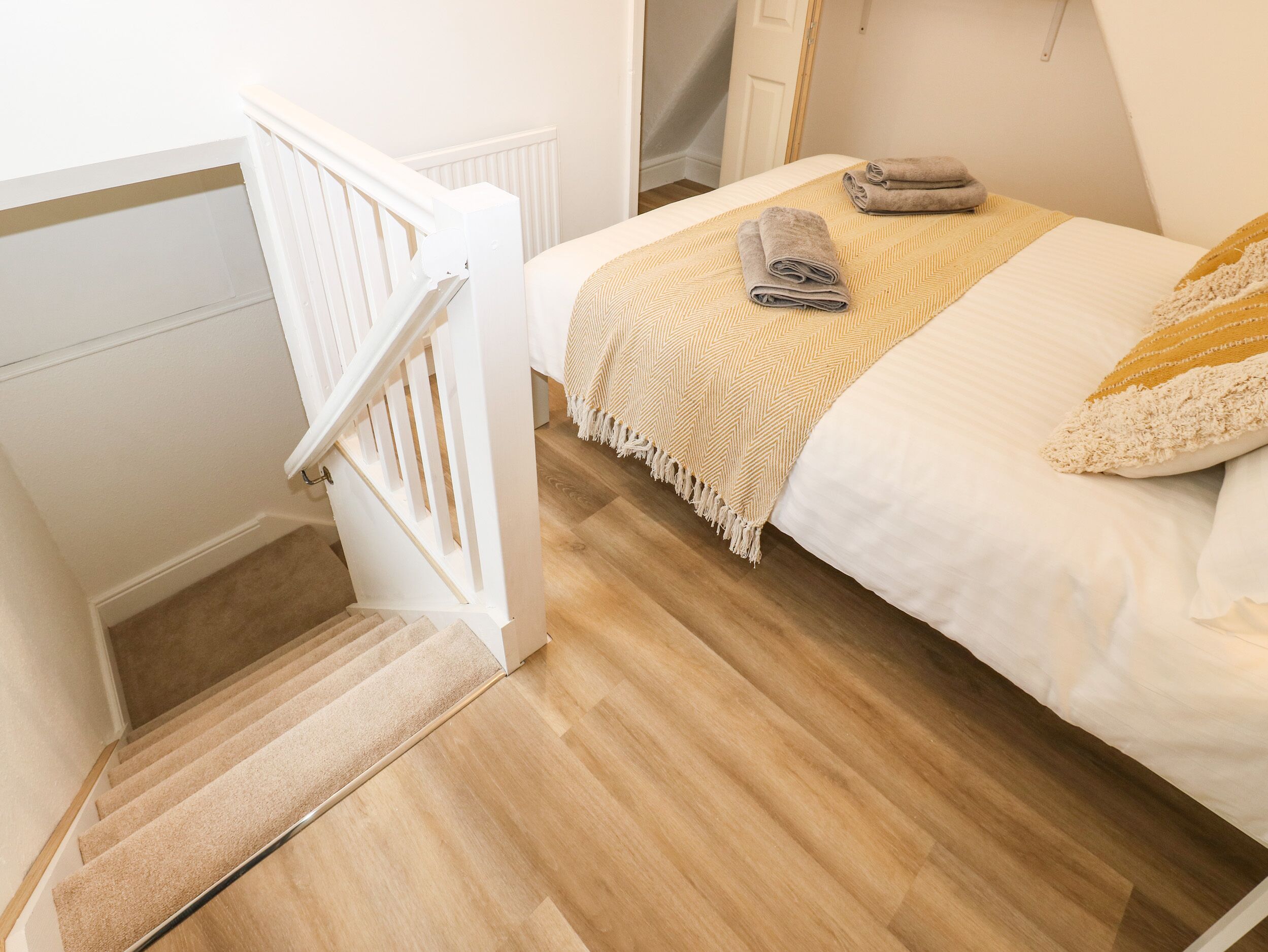 Un dormitorio con una cama, una mesita de noche, una lámpara, un ventanal y una escalera.