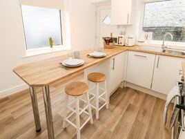 Una cucina moderna con piano di lavoro in legno, mobili bianchi, un lavello e due sgabelli.